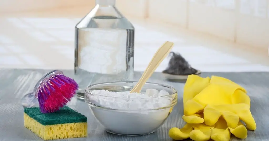 Bicarbonate of soda in a glass bowl with marigold gloves and scrubbing brushes ready for cleaning - Clean and Tidy Living