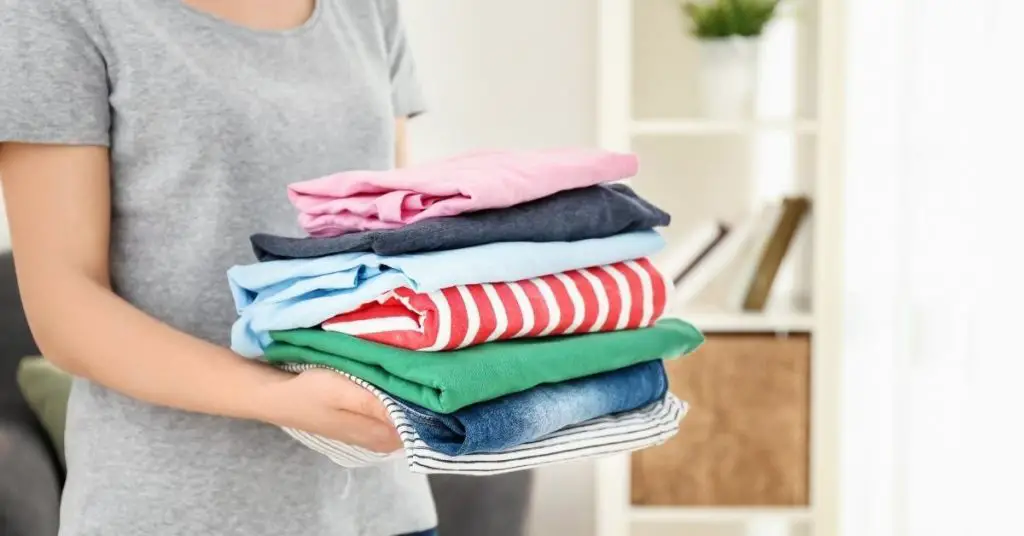 Bright clothes folded neatly after being laundered and being held by a woman - difference between bio and non bio