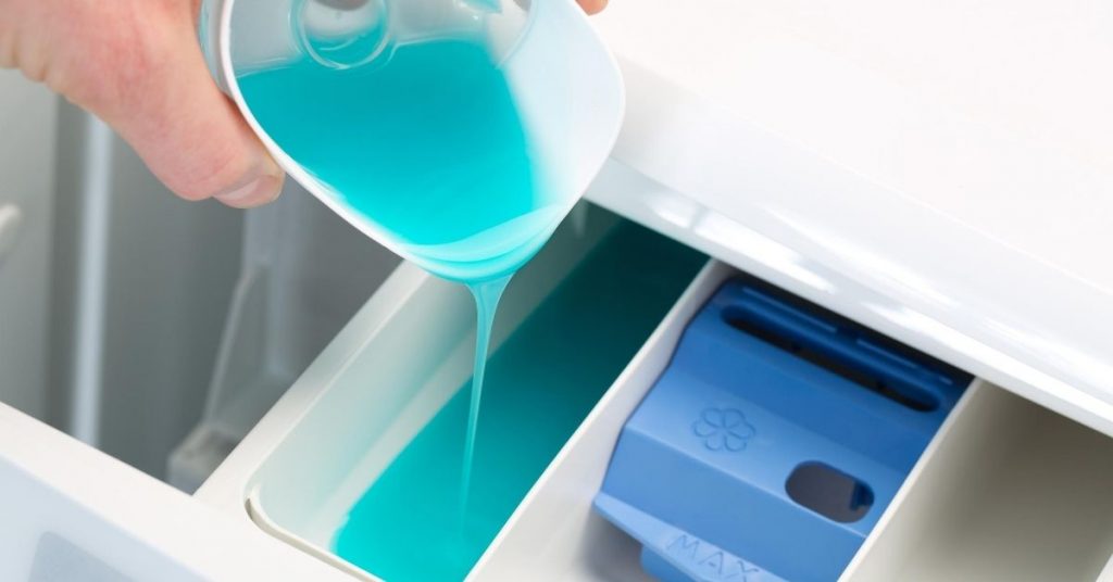 Person pouring laundry detergent into the drawer of a washing machine - Clean and Tidy Living