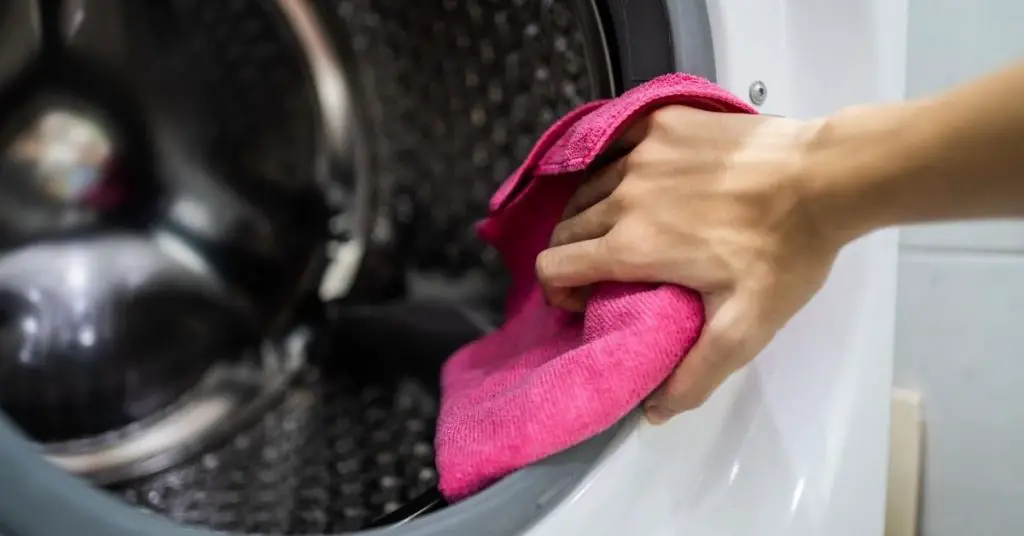 Woman cleaning a Washing Machine seal under £300 - Clean and Tidy Living