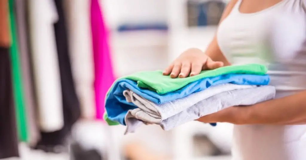 Woman holding folded clothes in hand - Tidy wardrobe