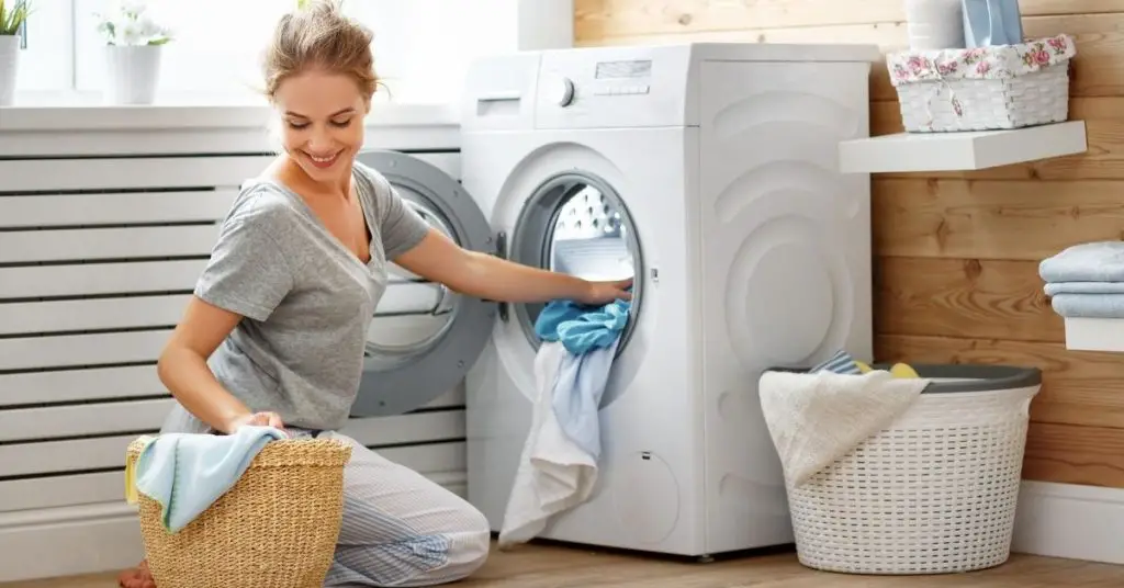 Woman putting clothes into a Washing Machine under £300 in a laundry room