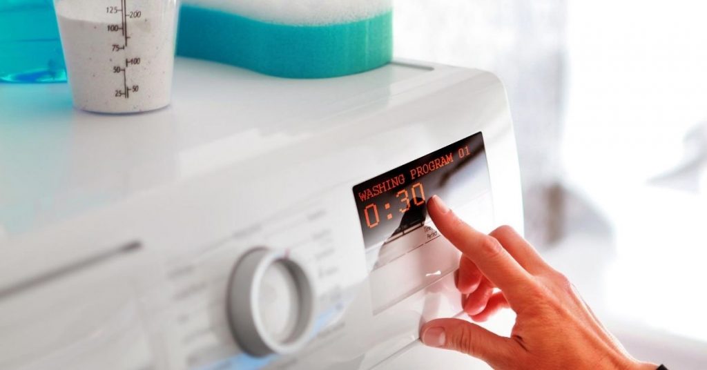 Woman turning on and setting a Washing Machine under £300 - Clean and Tidy Living