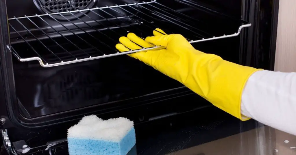 Cleaning an oven wearing marigold gloves - how to clean a self cleaning oven without using the self cleaning feature - Clean and Tidy Living