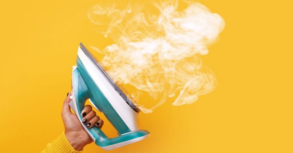 Person using the steam from an iron to get a sick stain out of a carpet - Clean and Tidy Living